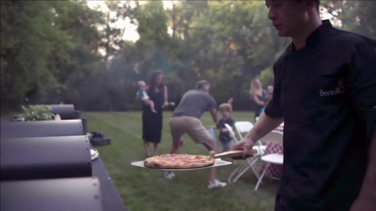 Friends around a Bertello oven at an evening party
